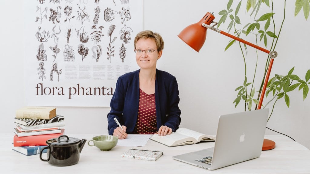 Die Übersetzerin und Lektorin Meike Blatzheim arbeitet am Schreibtisch mit Wörterbuch, Notizbuch, Tee und Notebook
